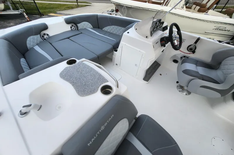 Slide: The Image of 2026 NauticStar 203 SC boat interior with gray seating, steering console, and cup holders. - 10