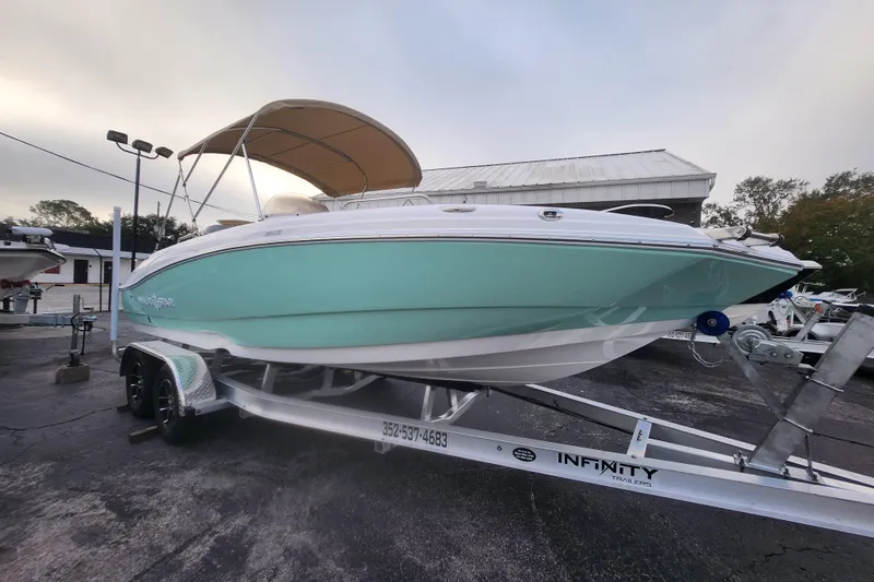 Slide: The Image of 2026 NauticStar 203 SC boat on trailer with canopy, displayed outdoors. - 13