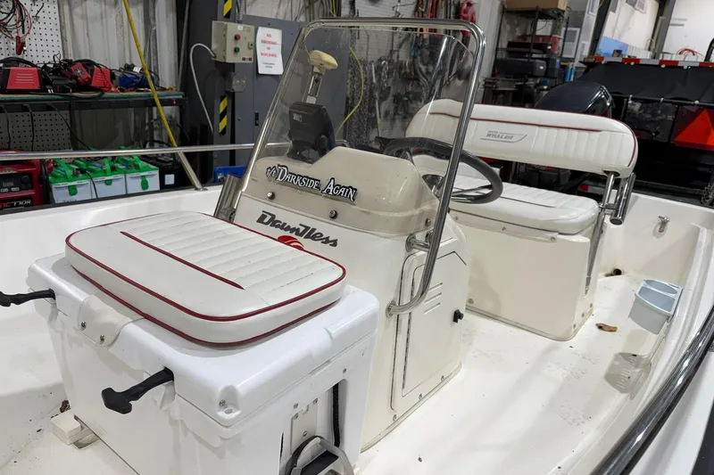 Slide: The Image of 1998 Boston Whaler Dauntless 13 boat interior with seating and steering console in a workshop. - 3