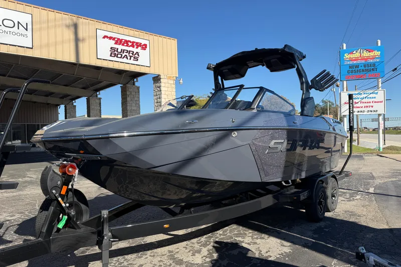 Slide: The Image of 2026 Supra SL 550 boat on trailer at dealership under clear blue sky. - 3