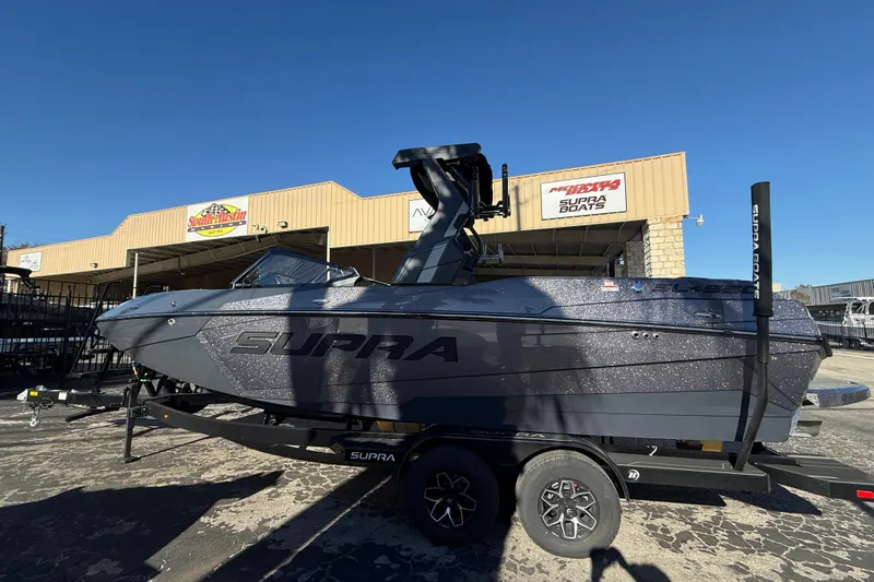 Slide: The Image of 2026 Supra SL 550 boat on trailer at dealership, sunny day. - 4