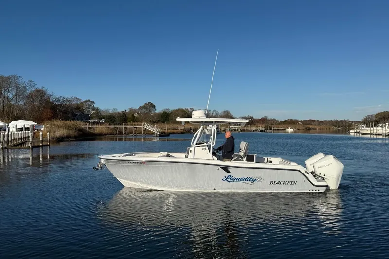Slide: The Image of 2022 Blackfin 252 CC boat cruising on a calm river under a clear blue sky. - 0