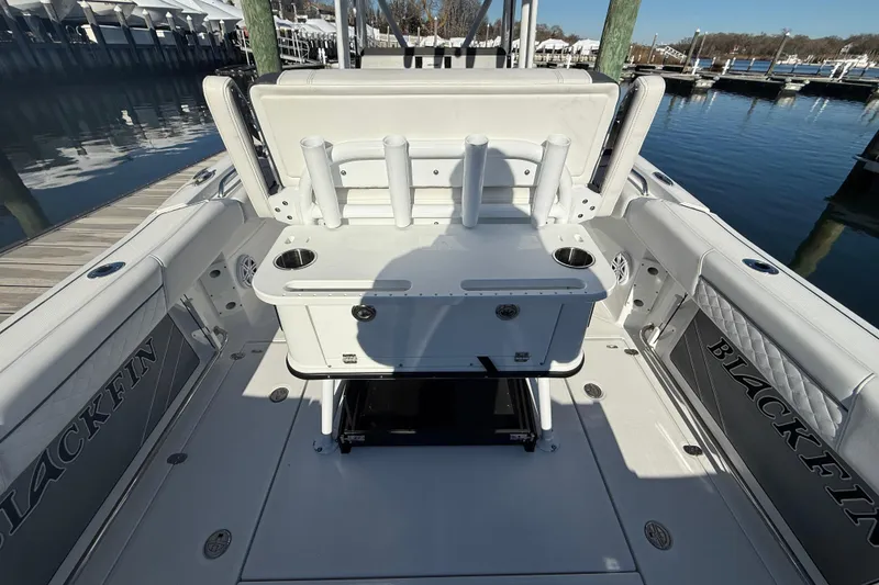 Slide: The Image of 2022 Blackfin 252 CC boat interior with rod holders and seating at a marina. - 15