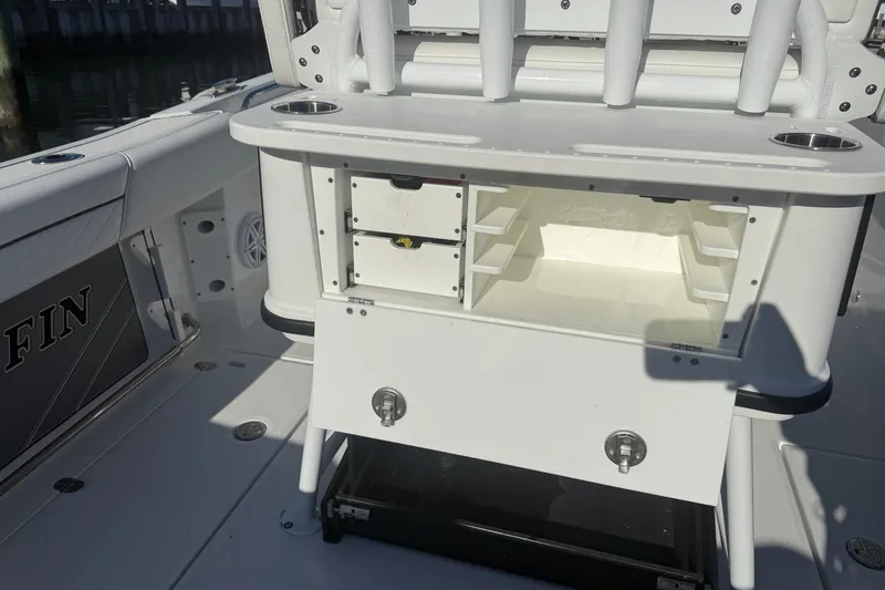Slide: The Image of 2022 Blackfin 252 CC boat interior with open storage compartment and rod holders. - 17