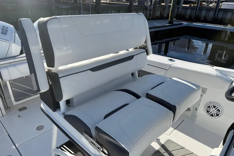 Slide: The Image of 2022 Blackfin 252 CC boat seating with white and black upholstery, docked by the water. - 21