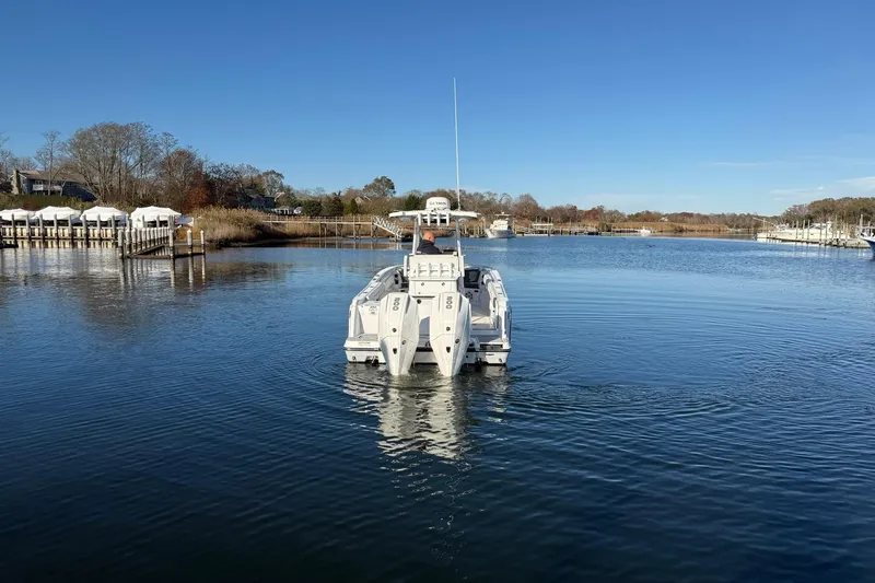 Slide: The Image of 2022 Blackfin 252 CC boat cruising on a calm river under a clear blue sky. - 3