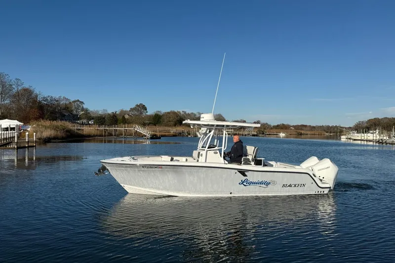 Slide: The Image of 2022 Blackfin 252 CC boat cruising on a calm river under a clear blue sky. - 47