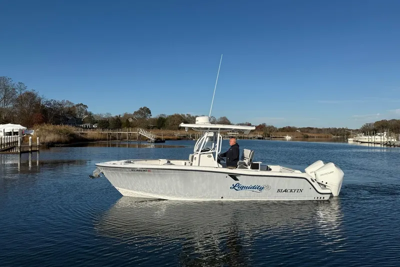 Slide: The Image of 2022 Blackfin 252 CC boat cruising on a calm river under a clear blue sky. - 48