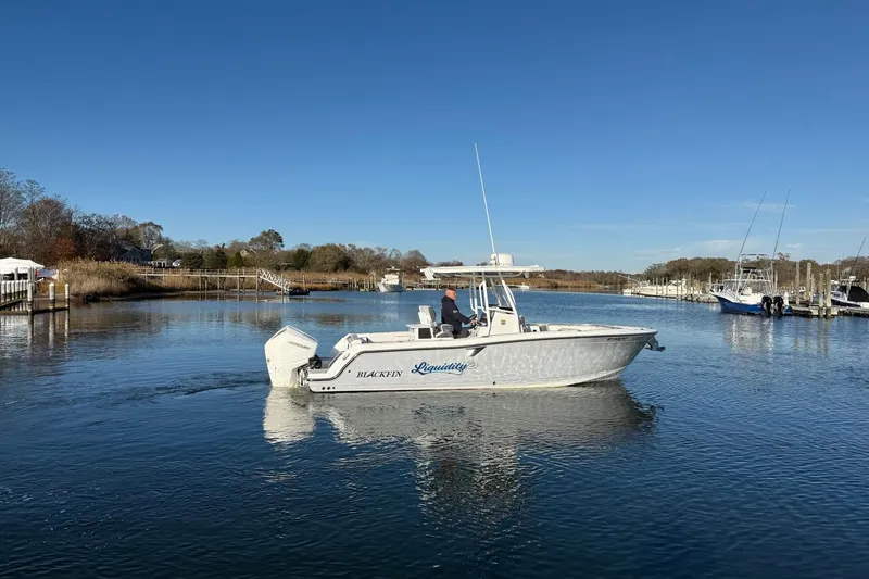 Slide: The Image of 2022 Blackfin 252 CC boat cruising on a calm river under a clear blue sky. - 50