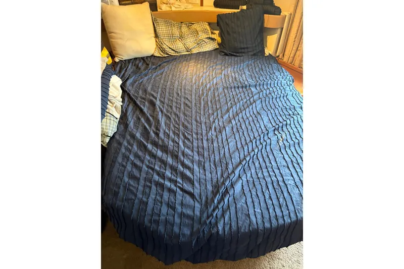 Slide: The Image of Bed with blue textured cover and assorted pillows inside a 2005 Carver 41 Cockpit Motor Yacht. - 11