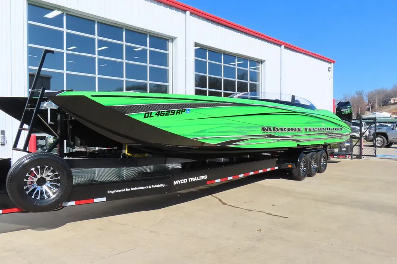 Slide: The Image of 2023 MTI 390X powerboat in vibrant green on a trailer outside a garage. - 13
