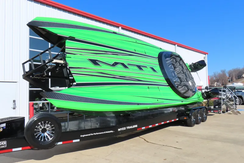 Slide: The Image of 2023 MTI 390X powerboat in vibrant green on a trailer outside a building. - 2