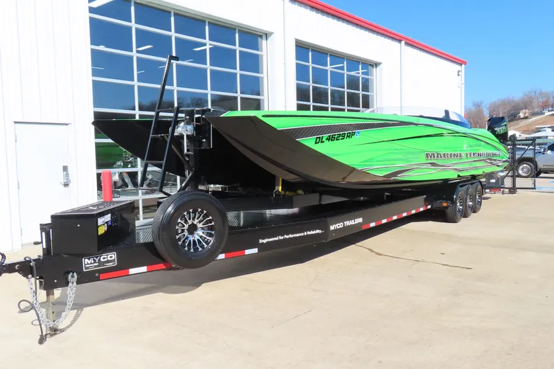 Slide: The Image of 2023 MTI 390X powerboat in vibrant green on a Myco trailer outside a garage. - 38