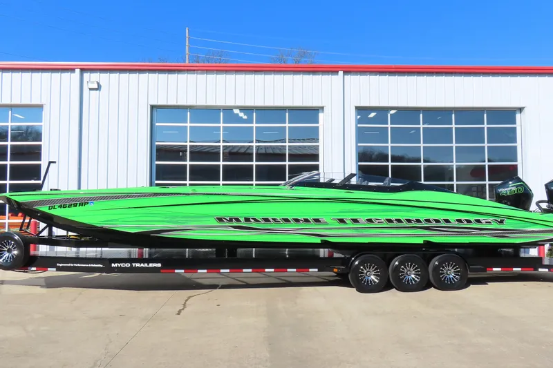 Slide: The Image of Bright green 2023 MTI 390X speedboat on trailer, parked outside a garage. - 7