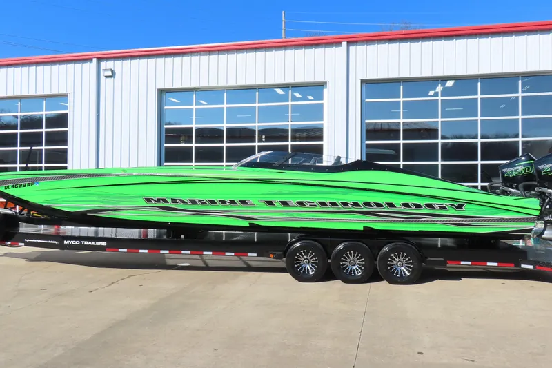 Slide: The Image of 2023 MTI 390X powerboat in vibrant green on a trailer, parked outside a garage. - 8