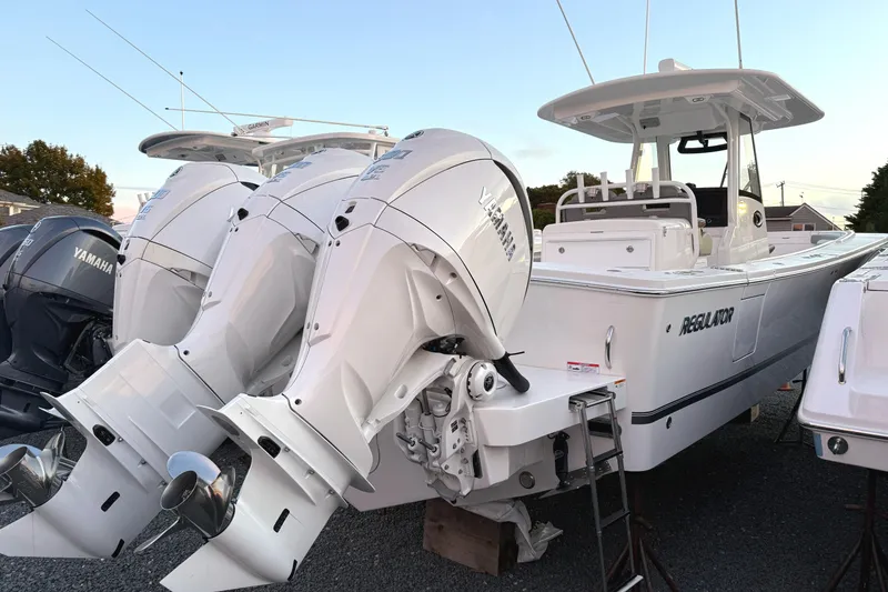 Slide: The Image of 2024 Regulator 34 boat with twin Yamaha outboard engines, docked on gravel. - 2