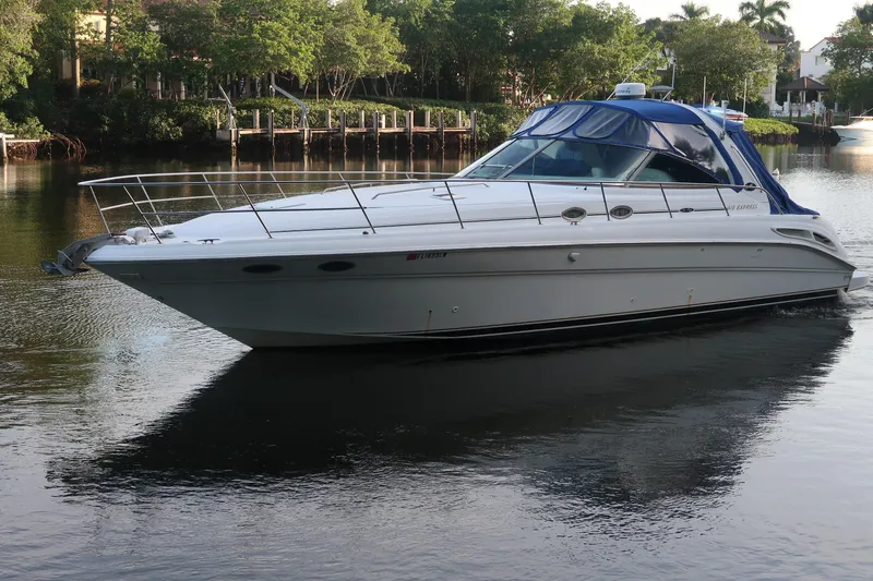 Slide: The Image of 2002 Sea Ray 410 Sundancer yacht cruising on a calm river with lush greenery. - 10