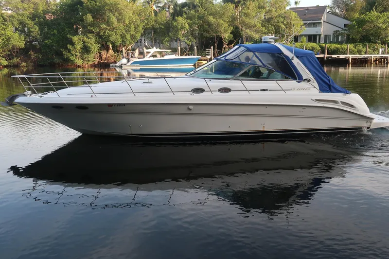 Slide: The Image of 2002 Sea Ray 410 Sundancer yacht cruising on calm water with lush greenery background. - 11