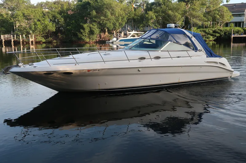 Slide: The Image of 2002 Sea Ray 410 Sundancer yacht on calm water, surrounded by lush greenery. - 12