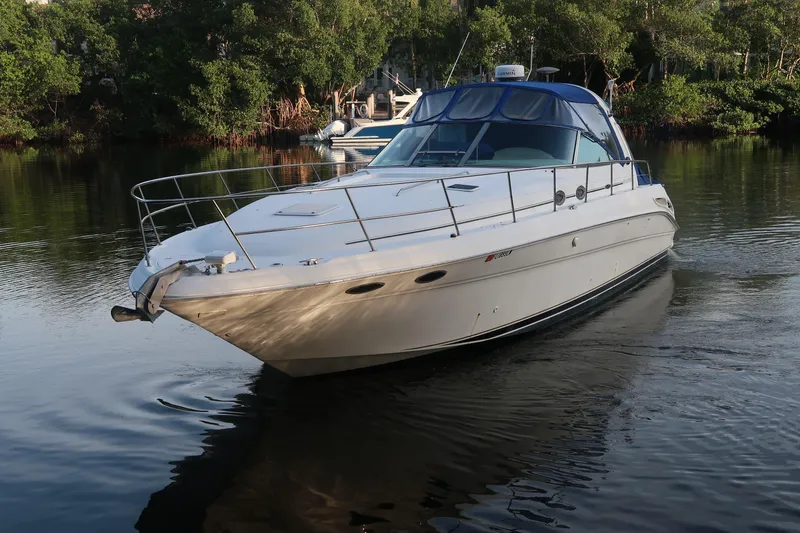 Slide: The Image of 2002 Sea Ray 410 Sundancer yacht on calm water, surrounded by lush greenery. - 13