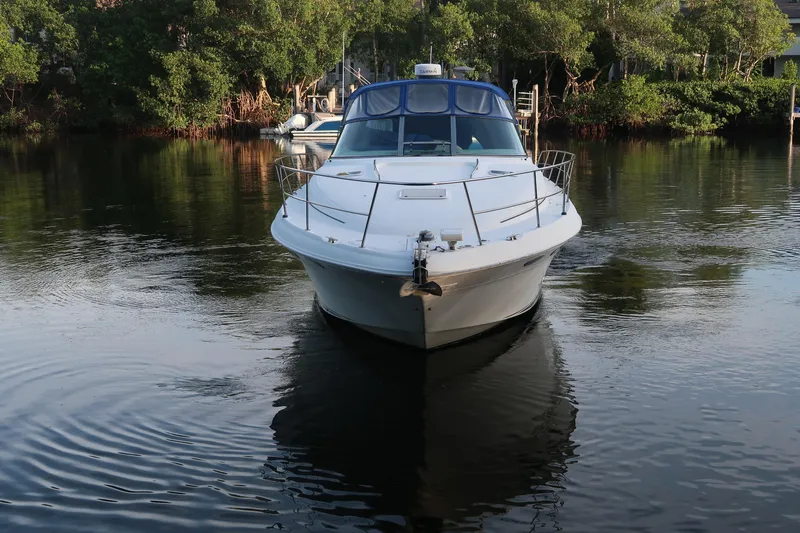 Slide: The Image of 2002 Sea Ray 410 Sundancer yacht on calm water, surrounded by lush greenery. - 14