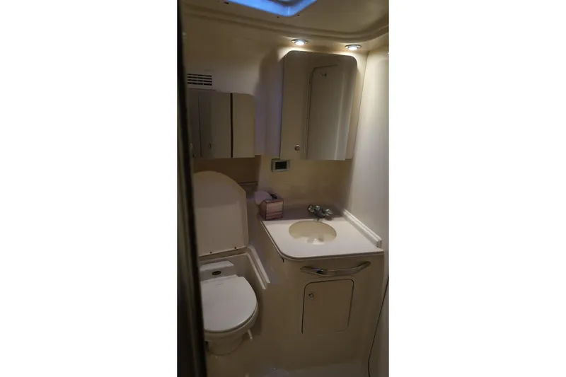 Slide: The Image of 2002 Sea Ray 410 Sundancer bathroom with sink, toilet, and storage cabinets. - 32