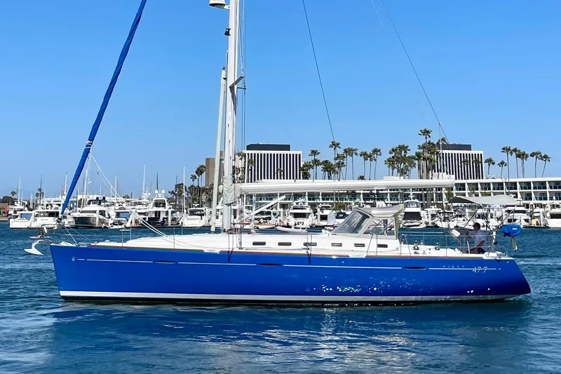 The Image of 2003 Beneteau First 47.7 sailboat with blue hull in marina setting. - 0