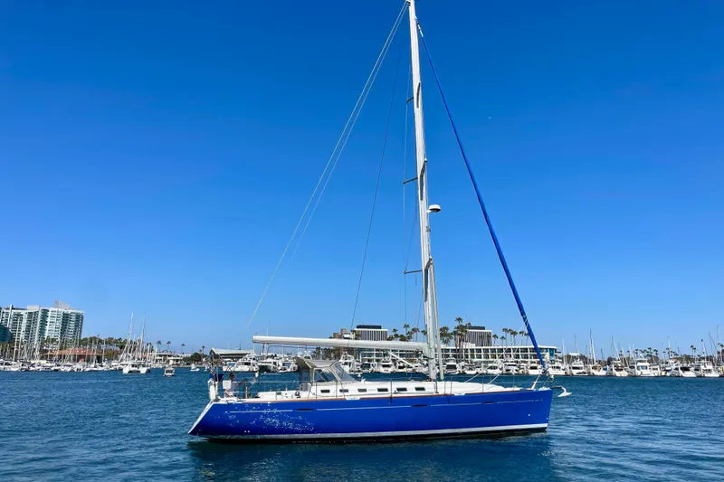 Slide: The Image of Blue 2003 Beneteau First 47.7 sailboat docked in a marina under clear blue skies. - 2