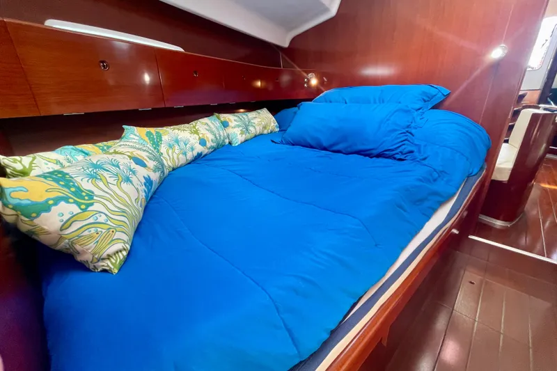 Slide: The Image of Cozy cabin interior of 2003 Beneteau First 47.7 yacht with blue bedding and decorative pillows. - 51