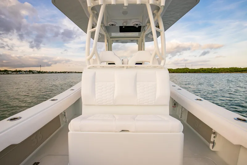 Slide: The Image of 2026 Yellowfin 36 Offshore boat interior with white seating, on calm water under a cloudy sky. - 24