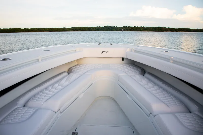 Slide: The Image of 2026 Yellowfin 36 Offshore boat interior with white cushioned seating on calm water. - 29