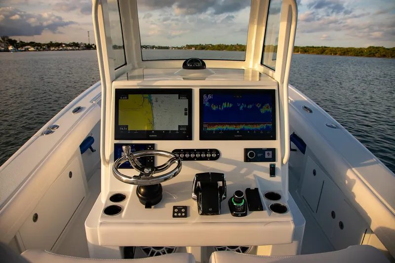 Slide: The Image of 2026 Yellowfin 36 Offshore boat dashboard with dual navigation screens on calm water. - 52