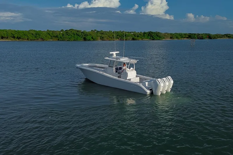 Slide: The Image of 2026 Yellowfin 36 Offshore boat on calm water with lush green shoreline. - 90