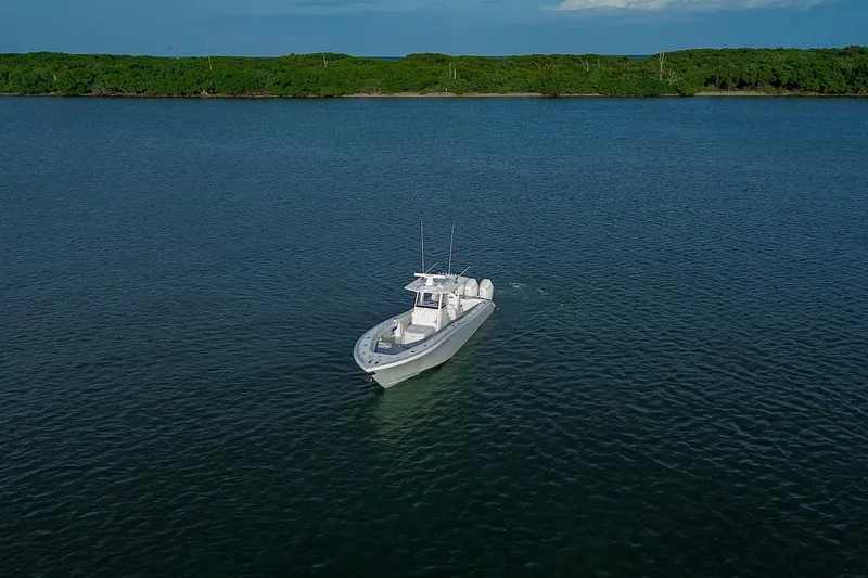 Slide: The Image of 2026 Yellowfin 36 Offshore boat cruising on calm waters near lush green shoreline. - 94