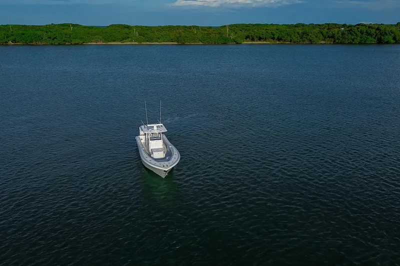 Slide: The Image of 2026 Yellowfin 36 Offshore boat on calm water near lush green shoreline. - 95