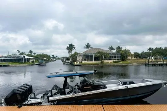 The Image of 2025 Nor-Tech 400 Supersport boat docked by a scenic waterfront with palm trees. - 1