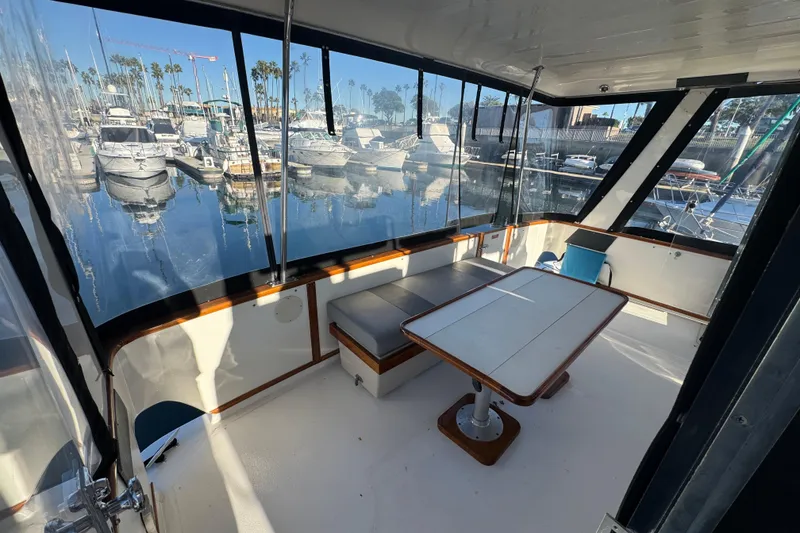 Slide: The Image of 1990 Sea Ray 380 Aft Cabin yacht interior with marina view, featuring seating and table. - 16