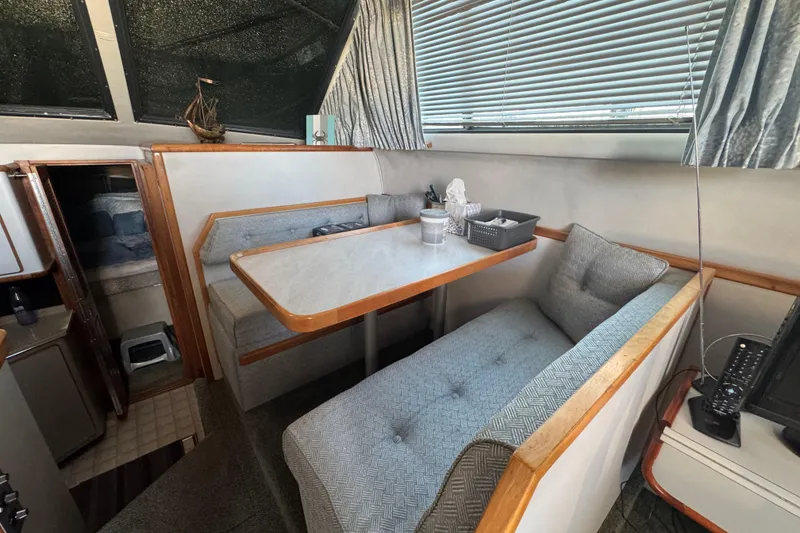 Slide: The Image of 1990 Sea Ray 380 Aft Cabin interior with cozy dining area and cushioned seating. - 27