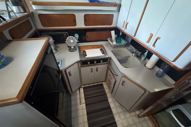 Slide: The Image of 1990 Sea Ray 380 Aft Cabin kitchen with cabinets, sink, and appliances. - 29