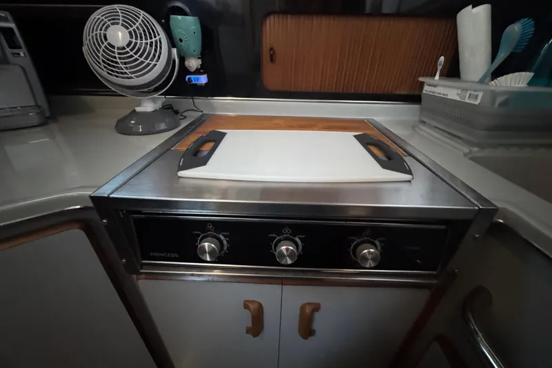 Slide: The Image of 1990 Sea Ray 380 Aft Cabin kitchen with stove, cutting board, and fan. - 31