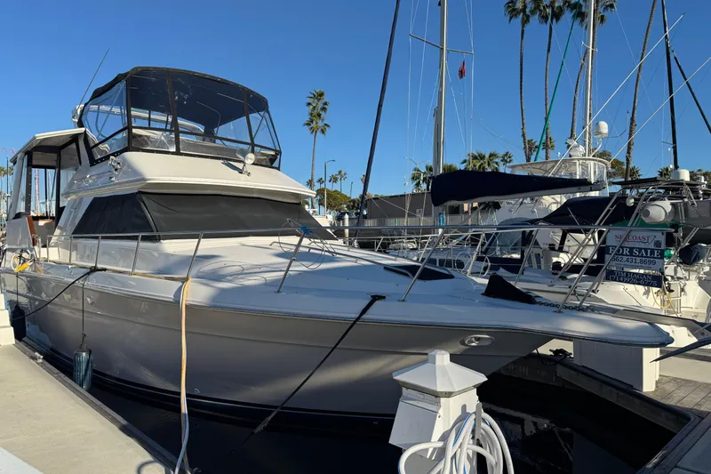 Slide: The Image of 1990 Sea Ray 380 Aft Cabin yacht docked, for sale, with clear blue sky background. - 5