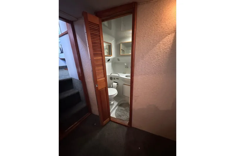 Slide: The Image of 1990 Sea Ray 380 Aft Cabin bathroom with wooden door and compact design. - 50
