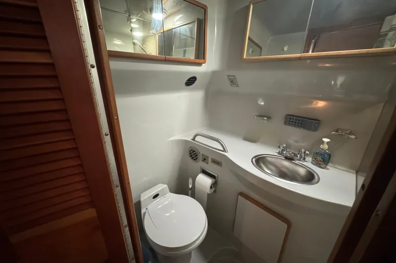 Slide: The Image of 1990 Sea Ray 380 Aft Cabin bathroom with sink, toilet, and mirror. - 51