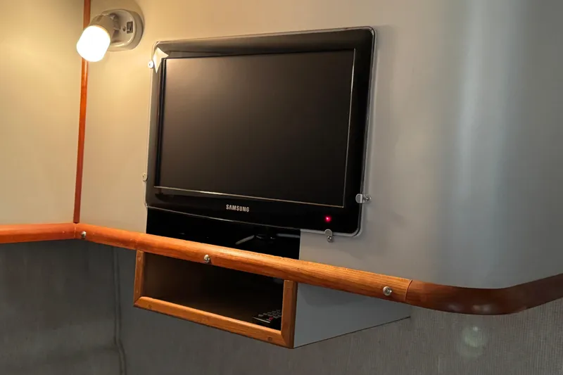 Slide: The Image of 1990 Sea Ray 380 Aft Cabin interior with wall-mounted Samsung TV and wooden shelf. - 53