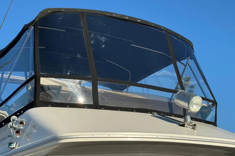 Slide: The Image of 1990 Sea Ray 380 Aft Cabin boat with clear enclosure and spotlight, under blue sky. - 6
