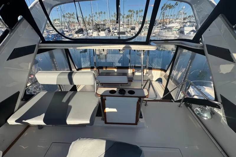 Slide: The Image of 1990 Sea Ray 380 Aft Cabin interior with marina view, featuring seating and helm area. - 62