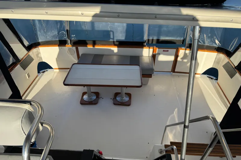 Slide: The Image of 1990 Sea Ray 380 Aft Cabin interior with seating and table, featuring wood accents. - 65
