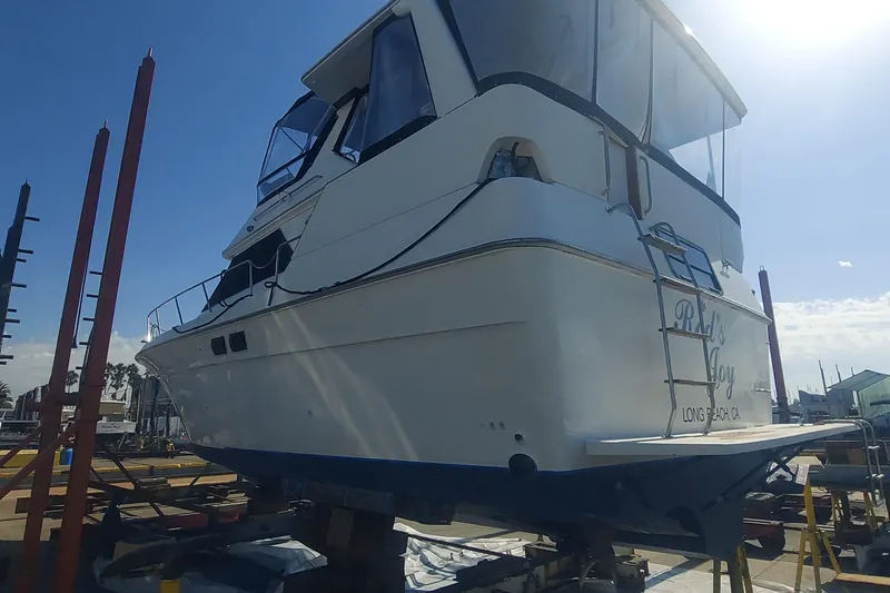 Slide: The Image of 1990 Sea Ray 380 Aft Cabin yacht on dry dock under clear blue sky. - 76