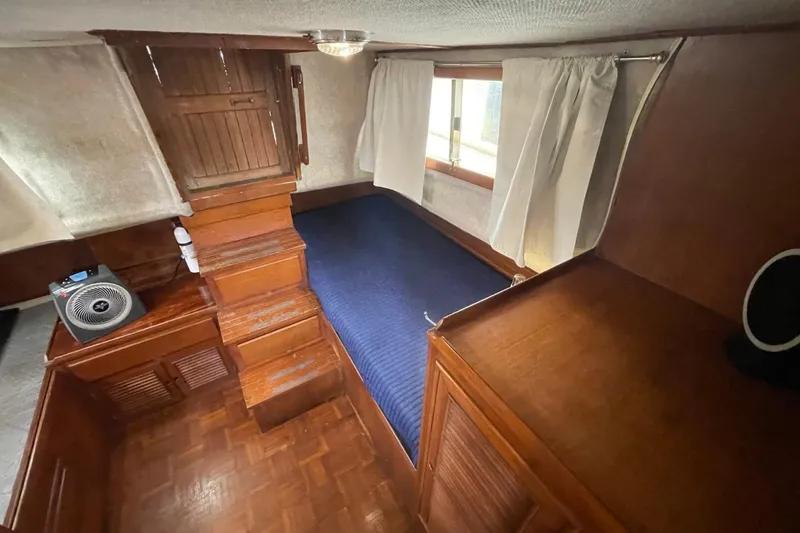 Slide: The Image of 1991 Marine Trader 34 Double Cabin interior with wooden finish and blue bedding. - 28