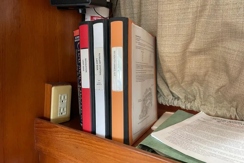 Slide: The Image of Books and manuals on a shelf inside a 1991 Marine Trader 34 Double Cabin boat. - 30